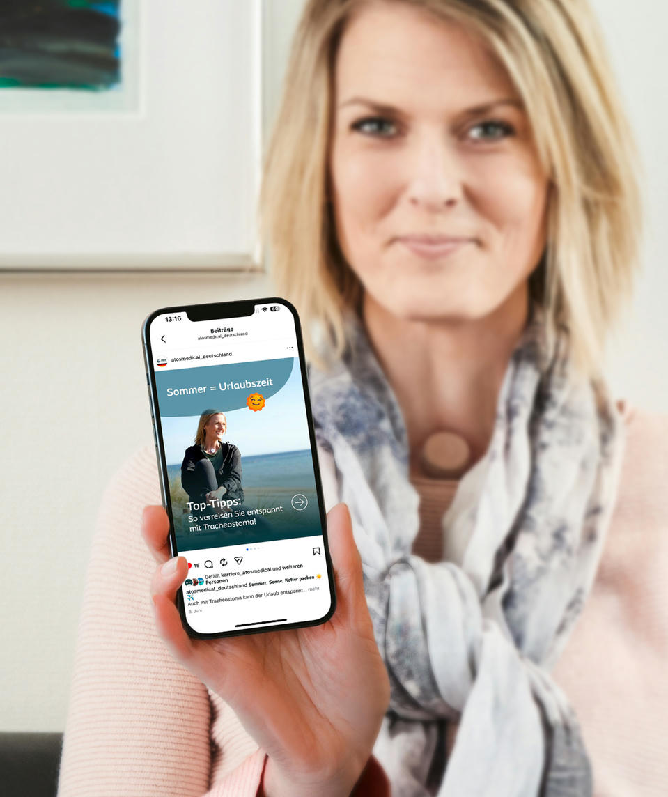 atos-medical-pat-insta-blue-1750x1000 Atos Medical - Frau mit einem Halsstoma zeigt den Atos Instagram Kanal auf dem Handy